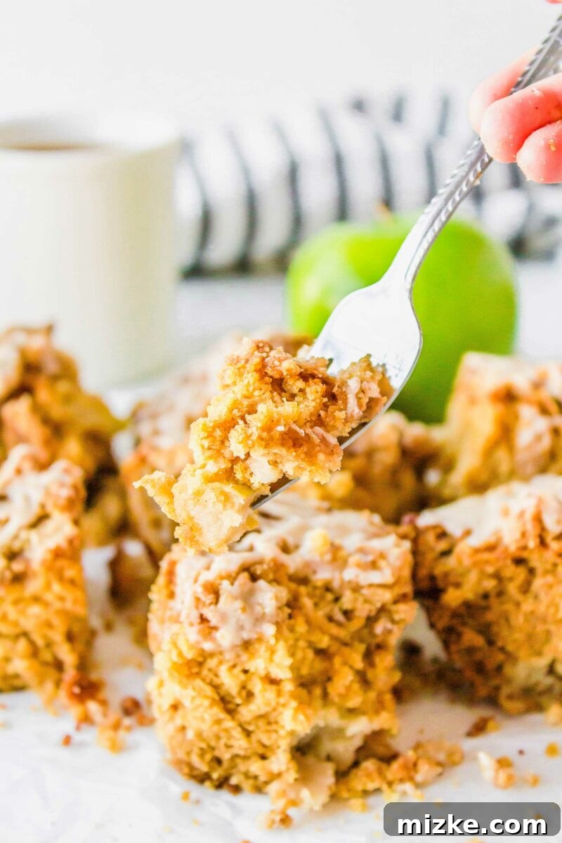 Cider Mill Coffee Cake 4 A bite-sized piece of coffee cake is being lifted by a fork from the plate, highlighting the glaze and streusel.