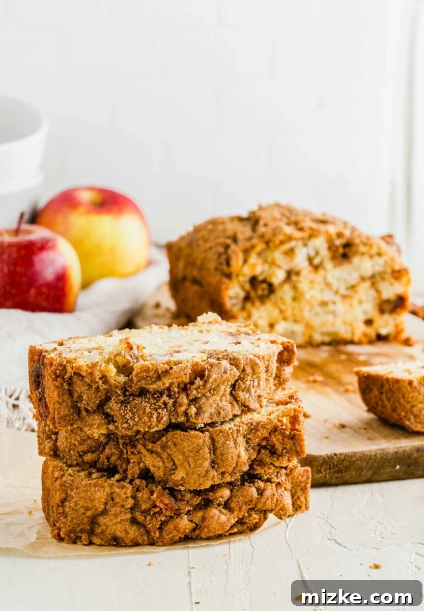Several slices of golden-brown apple cinnamon bread are stacked neatly on a kitchen countertop, ready to be enjoyed.
