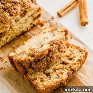 A top-down view of a freshly baked Apple Cinnamon Swirl Bread loaf, displaying a golden crust and a tempting swirl pattern.