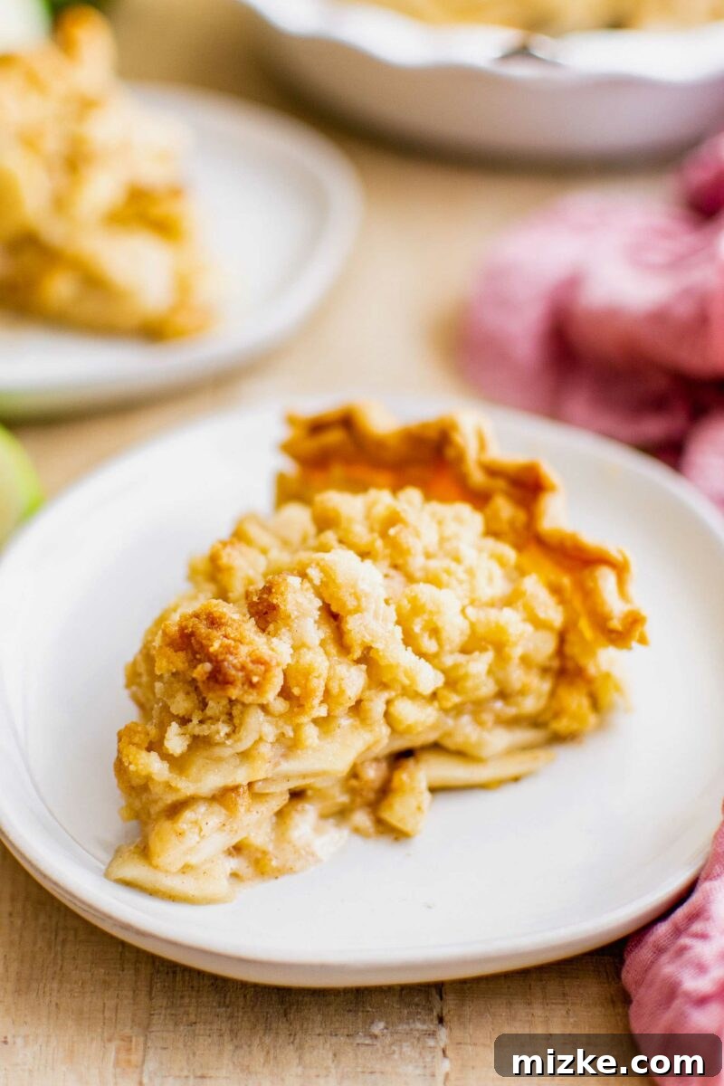 A beautifully presented slice of Dutch apple pie on a clean white round plate, ready to be enjoyed.