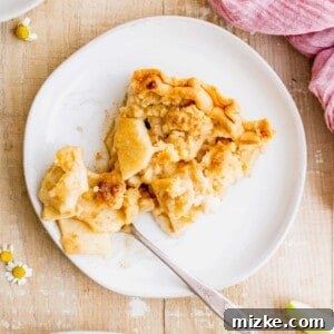 A close-up of a homemade Dutch apple pie, with its golden streusel topping and bubbling apple filling.