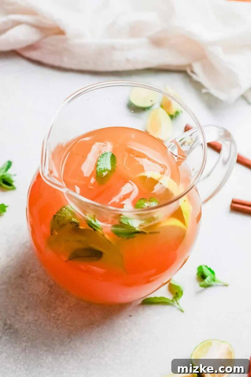 Crisp Apple Mojito 3 A pitcher of apple cider mojito is placed on a white surface, ready to be served.