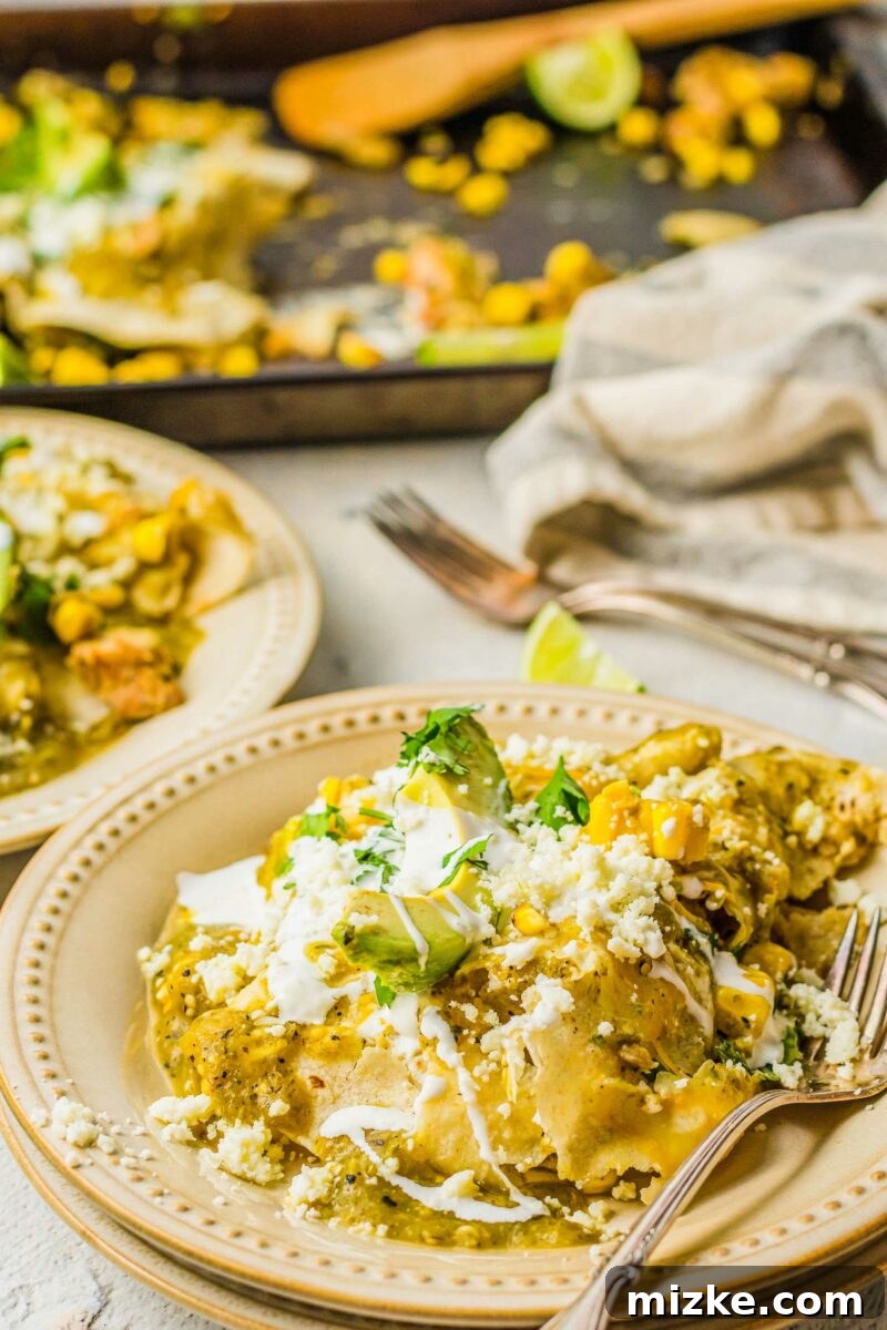 One-Pan Smoky Chipotle Chicken Enchiladas 5 A fork piercing a portion of a garnished chicken enchilada on a white plate, highlighting the tender chicken and melted cheese.