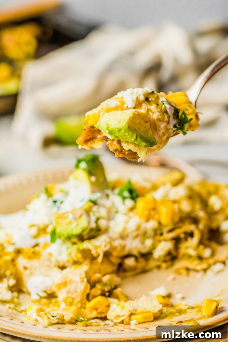 One-Pan Smoky Chipotle Chicken Enchiladas 6 A fork lifting a delicious, bite-sized piece of chicken enchilada from a garnished plate, ready to be enjoyed.