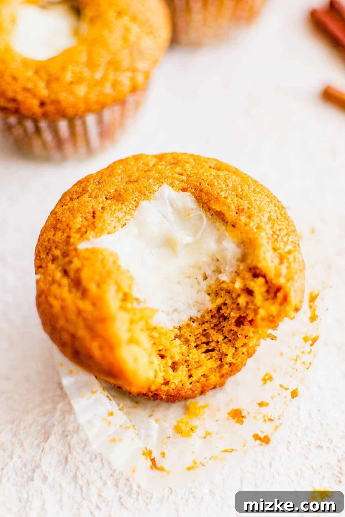 These Starbucks copycat pumpkin cream cheese muffins are soft, moist, and filled with gooey cream cheese and spice. Perfect for fall baking! A delicious homemade pumpkin cream cheese muffin with a bite taken out, revealing its soft texture and creamy filling.