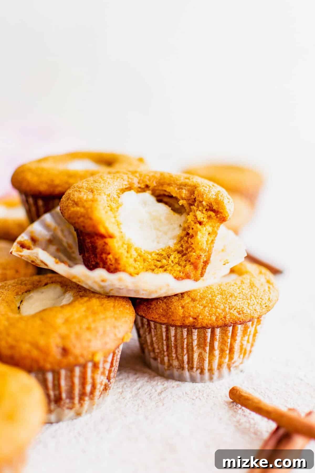 These Starbucks copycat pumpkin cream cheese muffins are soft, moist, and filled with gooey cream cheese and spice. Perfect for fall baking! A beautiful arrangement of stacked pumpkin cream cheese muffins, showcasing their golden tops and inviting appearance.