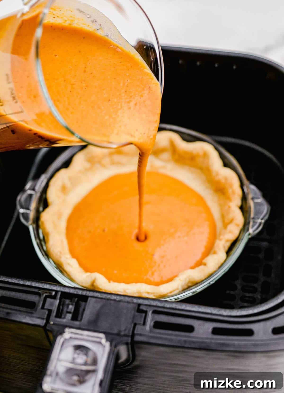 Pouring Pumpkin Pie Batter into a Crust Rich pumpkin pie filling being carefully poured into a blind-baked pie crust, set within a pie dish.