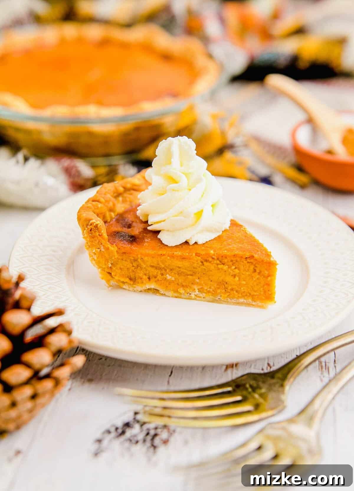 Served Air Fryer Pumpkin Pie Slice A inviting slice of air fryer pumpkin pie, adorned with a dollop of whipped cream, resting on a pristine white plate.