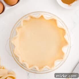 Air Fryer Pumpkin Perfection 2 A pie crust meticulously pressed into a scalloped pattern inside a clear glass baking dish.