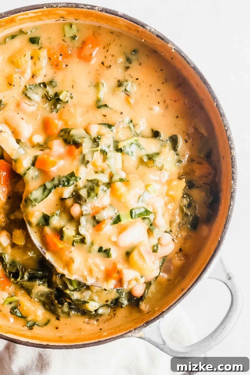 Plant-Based White Bean Comfort Stew 6 A large pot is filled with comforting vegan soup, a ladle ready to serve a delicious portion.