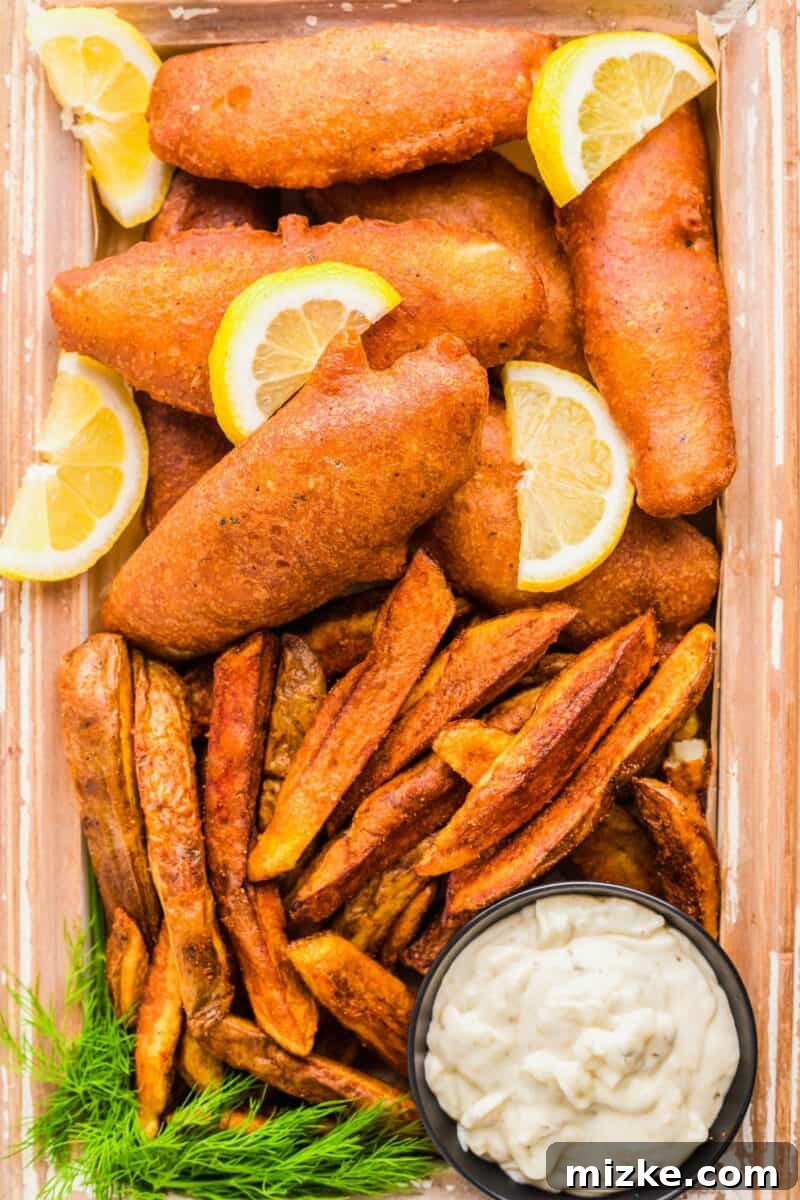 Golden Fried Perfection 2 Fried fish is served with lemon slices and fries with a side of tartar sauce.