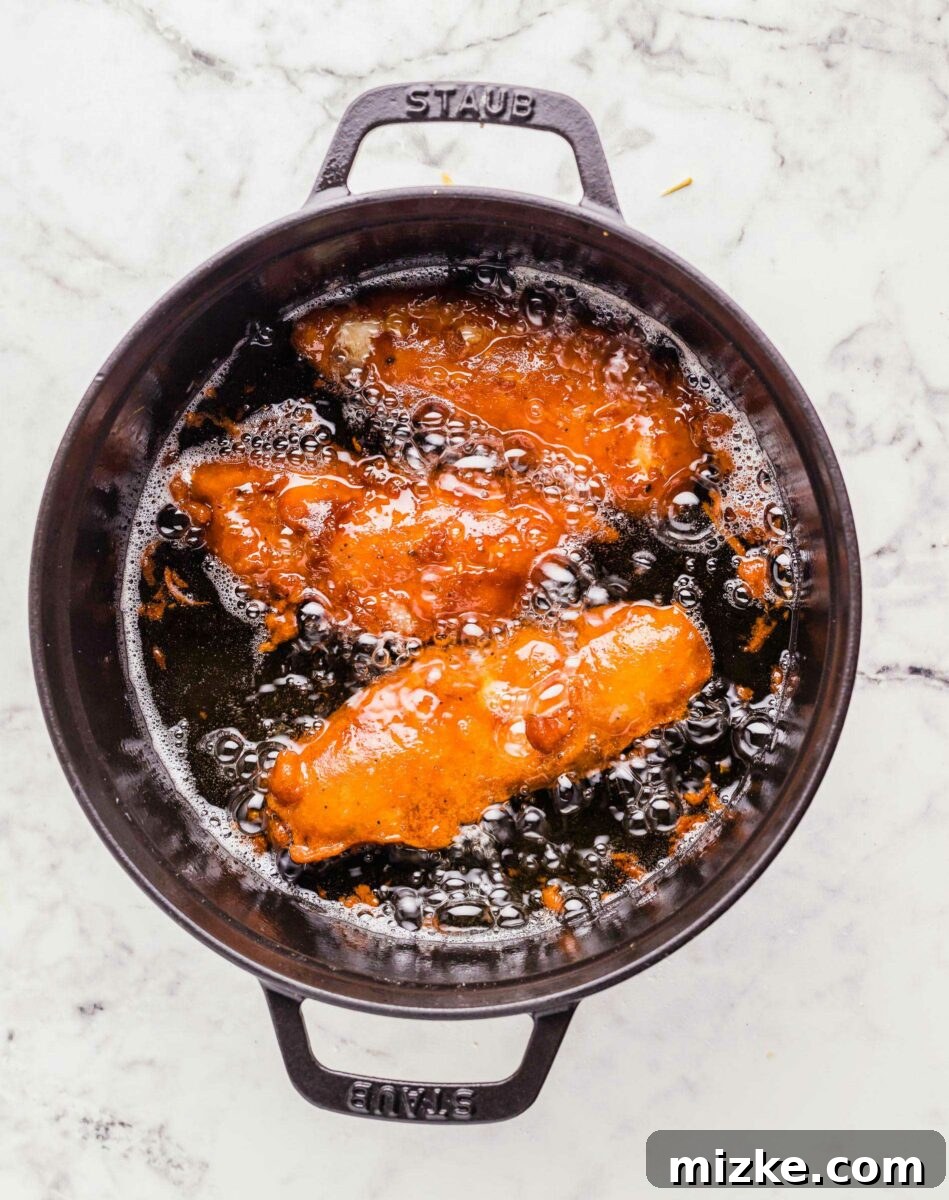 Golden Fried Perfection 5 Three pieces of fish are frying in a large black pot.