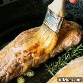 brushing maple mustard glaze on top of pork tenderloin