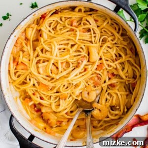 Spicy Cajun Shrimp Skillet Pasta 4 cajun shrimp pasta is in a large pot with a metal serving fork and spoon next to fresh parsley