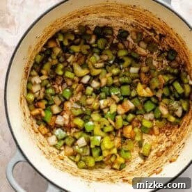 Hearty Chicken and Sausage Gumbo 9 Diced green bell peppers, onions, and celery are gently sautéing in a large pot, releasing their aromatic flavors and softening, a foundational and crucial step for any authentic gumbo.