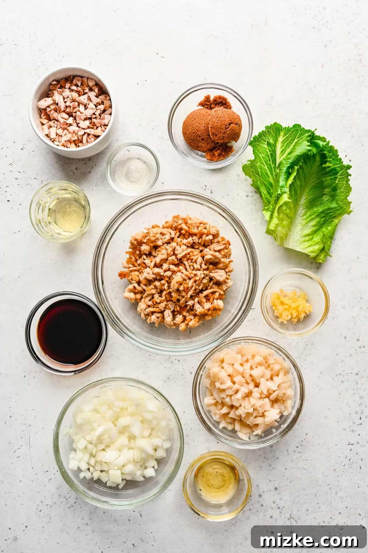 These chicken lettuce wraps are made with crisp lettuce, juicy ground chicken, tender shiitake mushrooms, and a sweet and tangy sauce! A visual display of fresh ingredients laid out for preparing chicken lettuce wraps, including ground chicken, mushrooms, and lettuce.