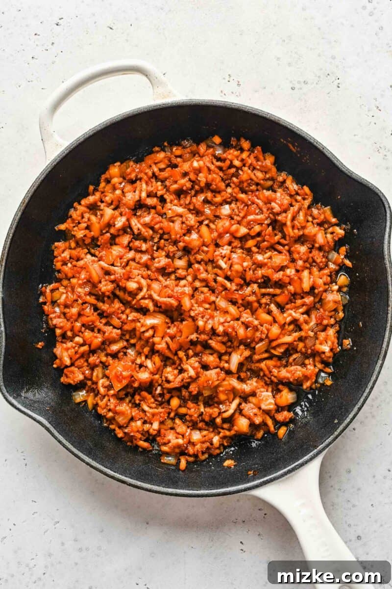 These chicken lettuce wraps are made with crisp lettuce, juicy ground chicken, tender shiitake mushrooms, and a sweet and tangy sauce! Seasoned ground chicken browning in a skillet, forming the savory base for the lettuce wraps.