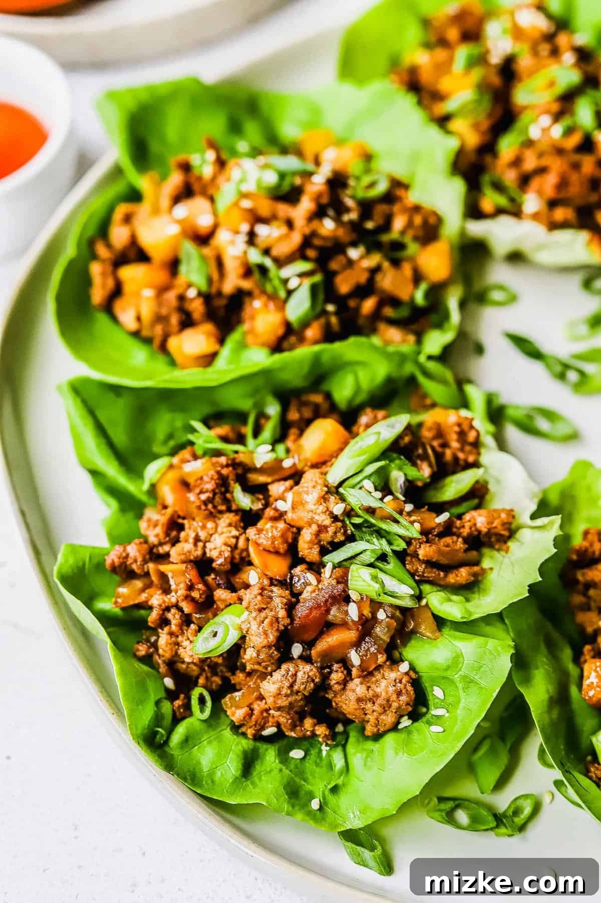 These chicken lettuce wraps are made with crisp lettuce, juicy ground chicken, tender shiitake mushrooms, and a sweet and tangy sauce! A perfectly assembled chicken lettuce wrap, showcasing the delicious ground chicken and mushroom filling in a fresh lettuce leaf.