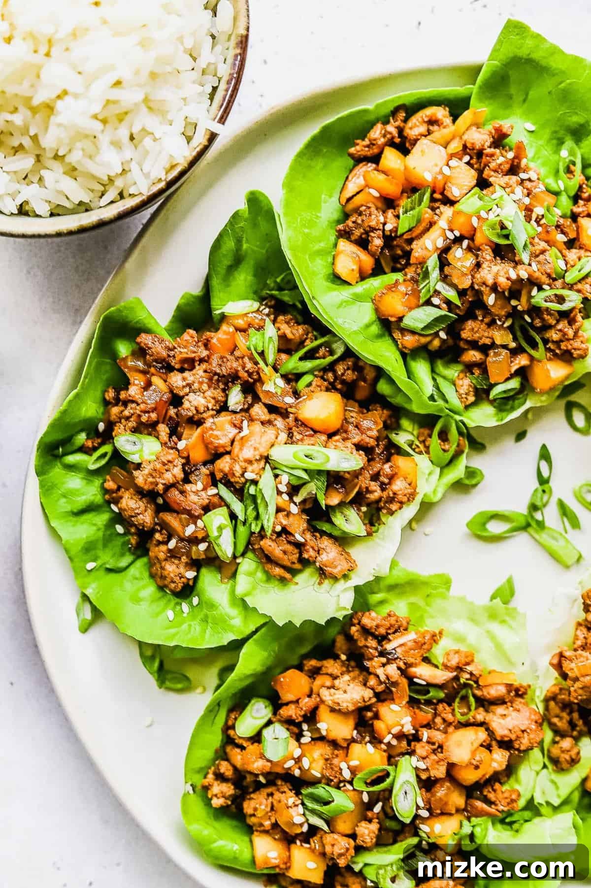 These chicken lettuce wraps are made with crisp lettuce, juicy ground chicken, tender shiitake mushrooms, and a sweet and tangy sauce! Finished chicken lettuce wraps, elegantly garnished with chopped green onions for a fresh touch.
