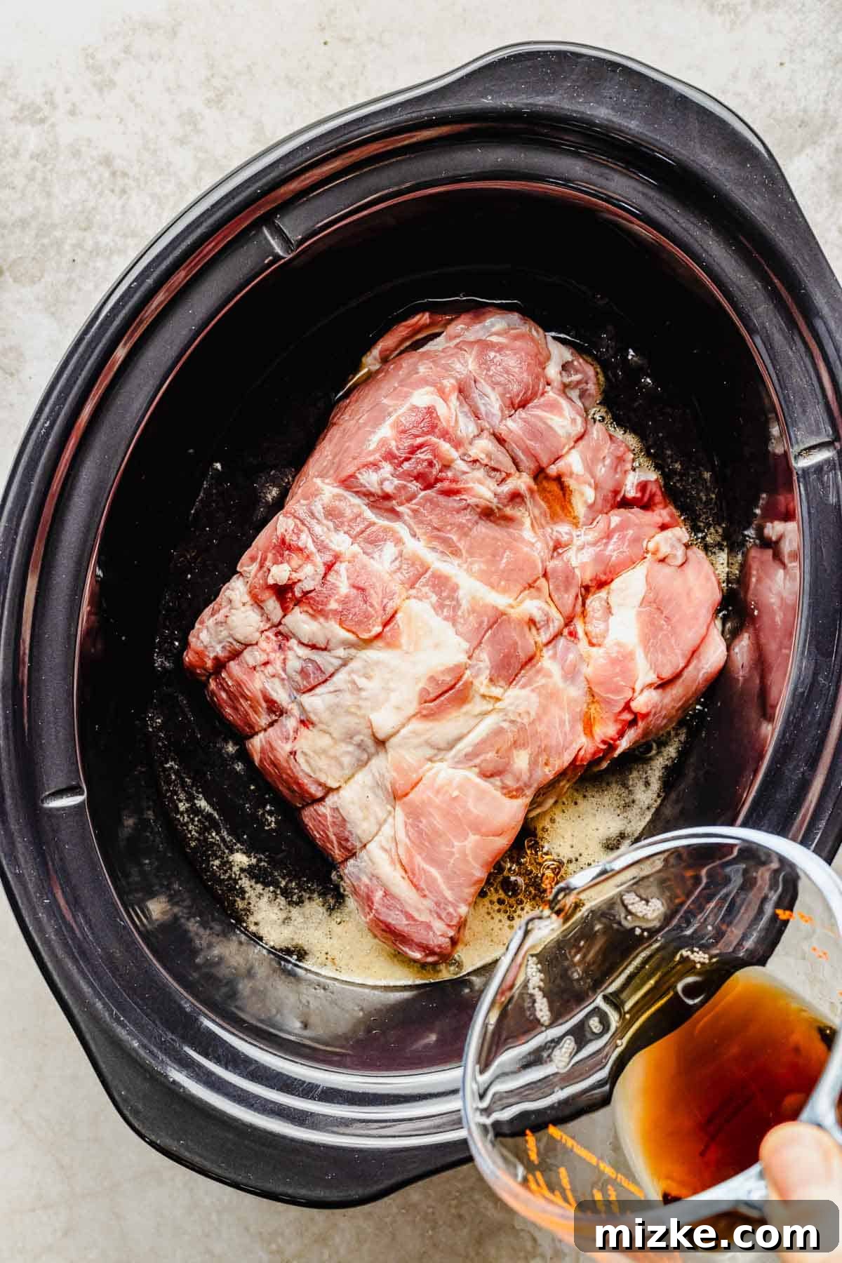 The initial step: pork and soda combined in the slow cooker for tender perfection. Pouring soda over a large piece of pork in a crock pot, preparing for slow cooking.