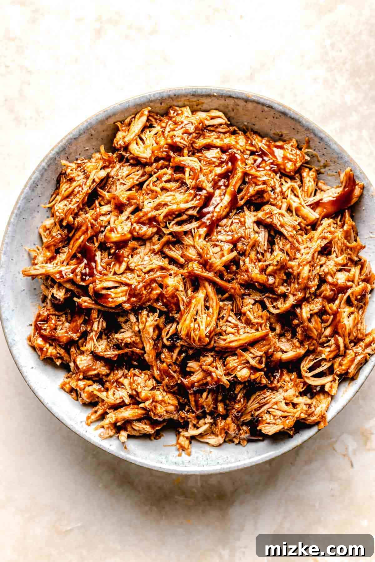 Achieving perfectly saucy pulled pork for your sliders. Combining shredded pork with rich BBQ sauce in a bowl, ensuring every piece is coated.