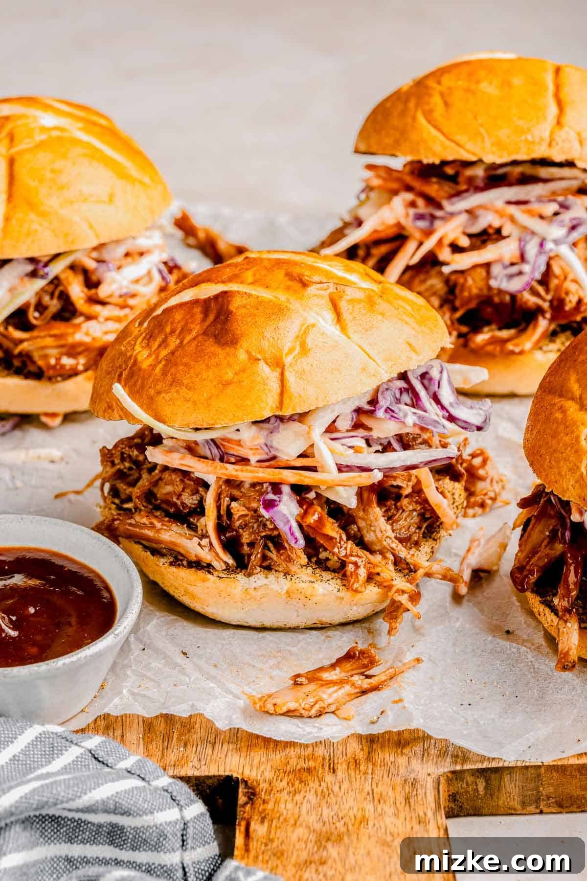 Serve with an extra side of BBQ sauce for dipping! A set of BBQ pulled pork sliders, with a small dish of extra BBQ sauce on the side.
