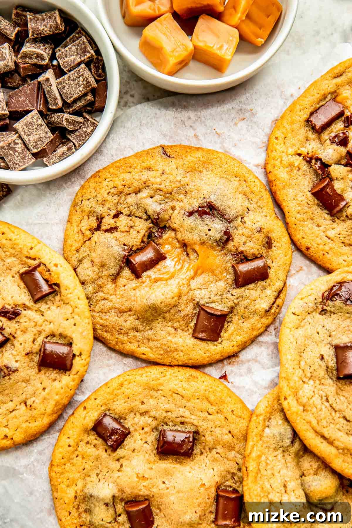 Molten Caramel Chocolate Chunk Cookies 2 several chocolate chunk stuffed caramel cookies on a piece of parchment paper