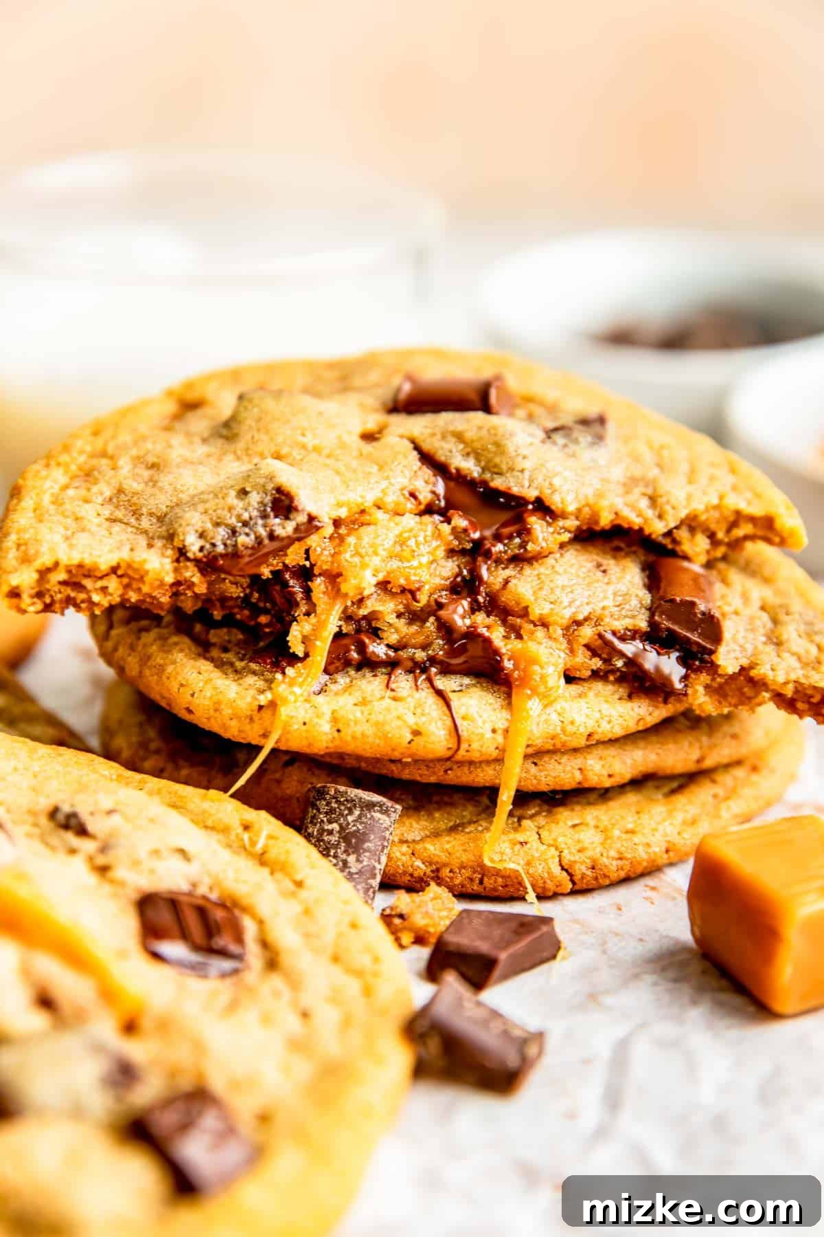 Molten Caramel Chocolate Chunk Cookies 4 half a caramel stuffed cookie is stacked on top of 3 other cookies with gooey caramel hanging off the side