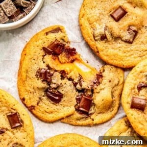a caramel stuffed cookie is split in half to show the gooey melted caramel in the center