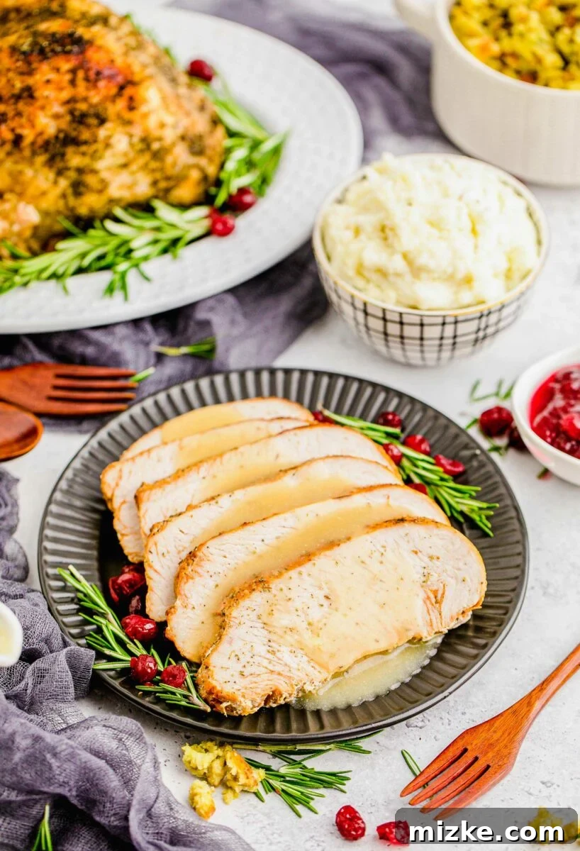 Perfect Instant Pot Turkey Breast 13 Elegant serving of sliced Instant Pot Turkey Breast on a black plate, with rosemary, cranberries, and a side of savory gravy.