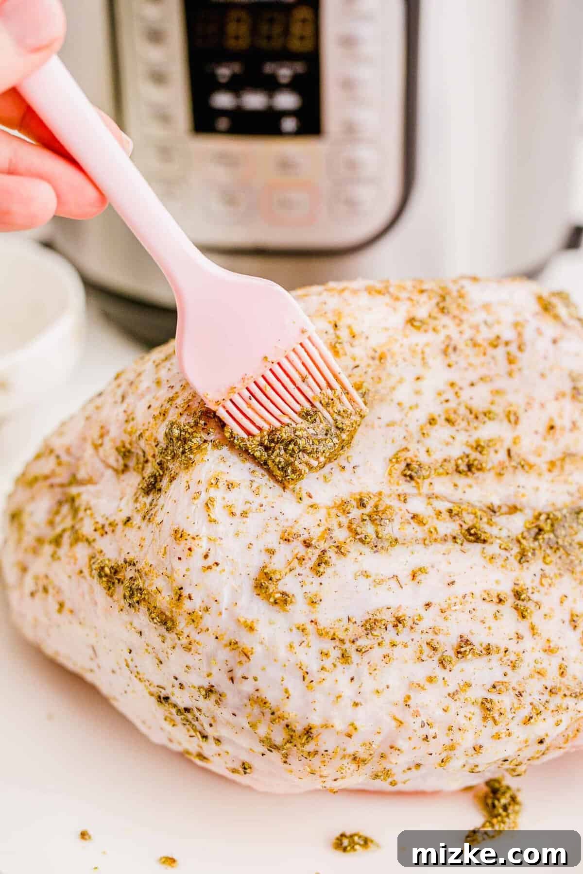 Perfect Instant Pot Turkey Breast 6 Brushing the aromatic spice mixture evenly onto the turkey breast using a pink silicone brush.