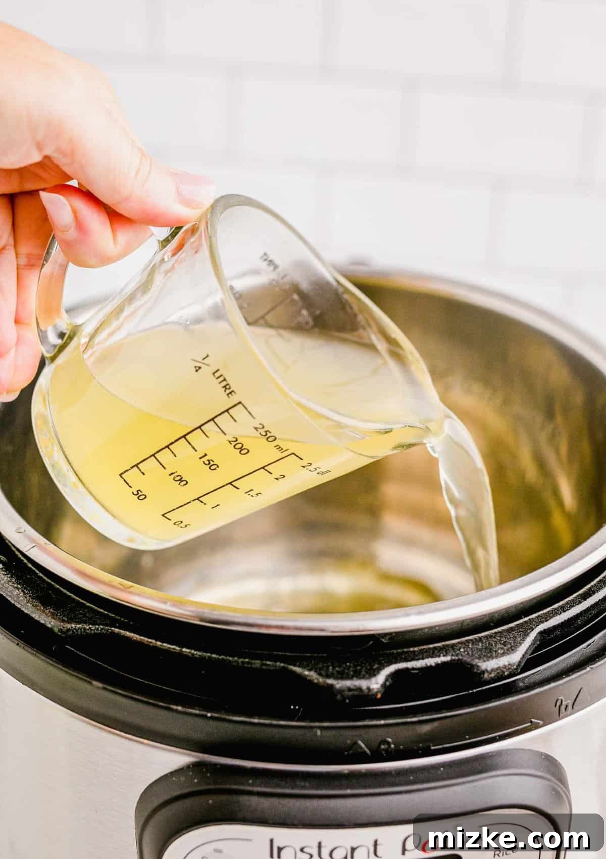 Perfect Instant Pot Turkey Breast 7 Pouring chicken stock into the insert of an Instant Pot, providing the liquid base for pressure cooking.