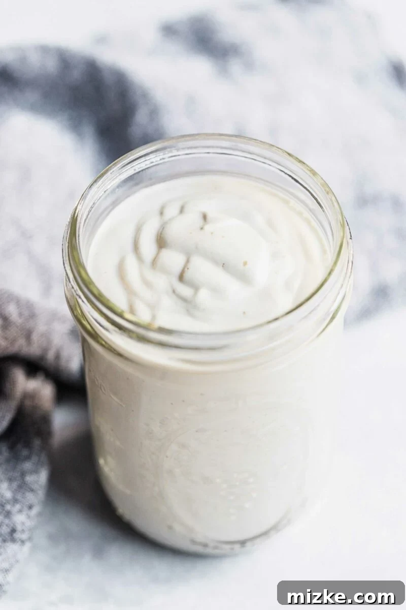Dreamy Vegan Cashew Cream 4 A perfectly smooth, white vegan cream sauce fills a glass mason jar to the very top.