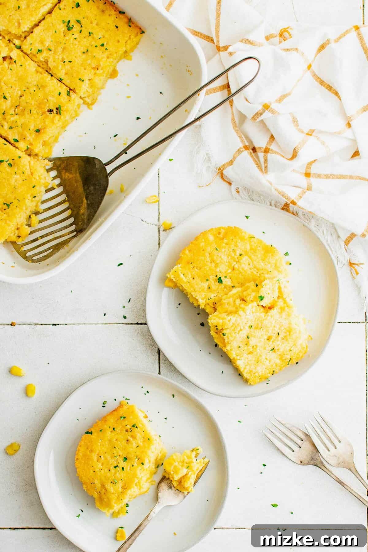 This easy cornbread casserole, made with Jiffy corn muffin mix and loaded with sweet corn, is a family favorite and perfect for any occasion. Serving a generous portion of golden-brown cornbread casserole onto plates, ready to be enjoyed by family and friends.