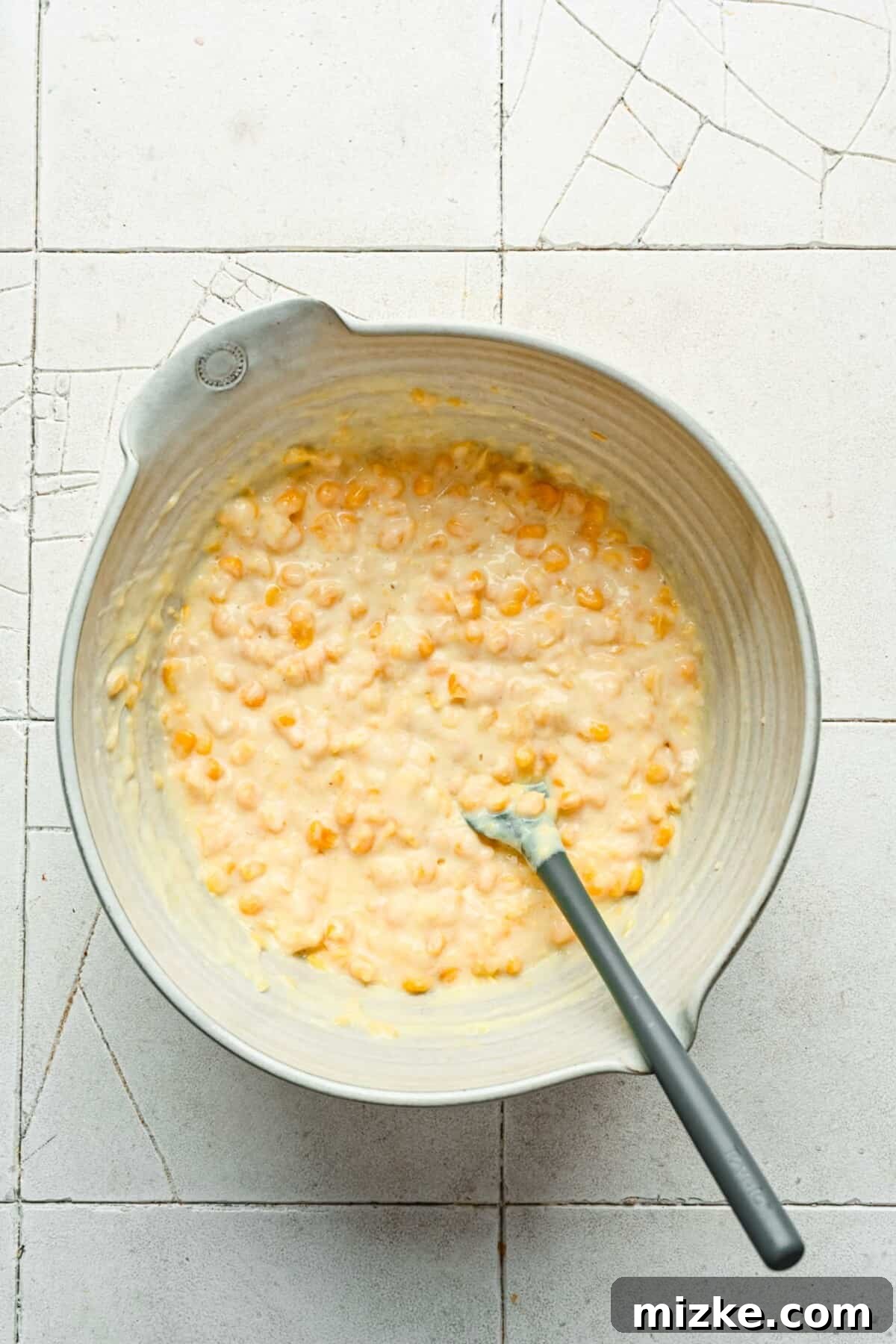 Hearty Cornbread Delight 3 Drained sweet corn and creamy cream-style corn are gently added to the wet mixture in a mixing bowl, ready to be incorporated into the cornbread casserole batter.