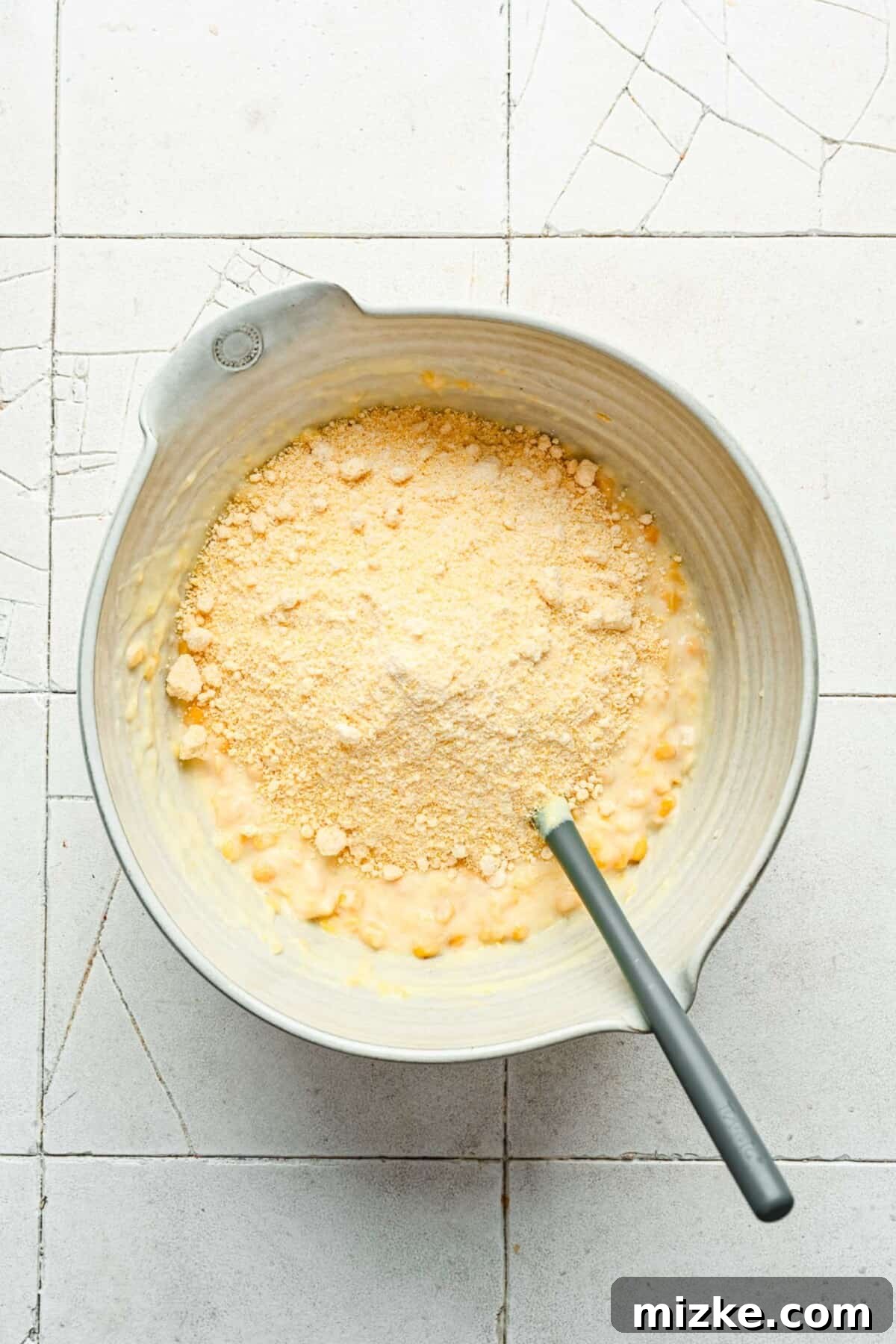 Hearty Cornbread Delight 4 The Jiffy corn muffin mix is carefully folded into the corn and wet ingredient mixture in a large bowl, creating the base for the delicious casserole.