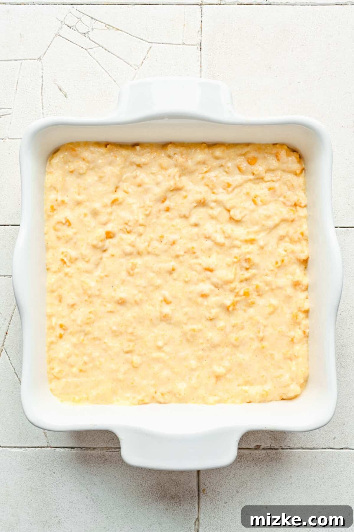 Hearty Cornbread Delight 5 The prepared cornbread casserole batter is evenly spread into a greased casserole dish, ready for baking to golden perfection.