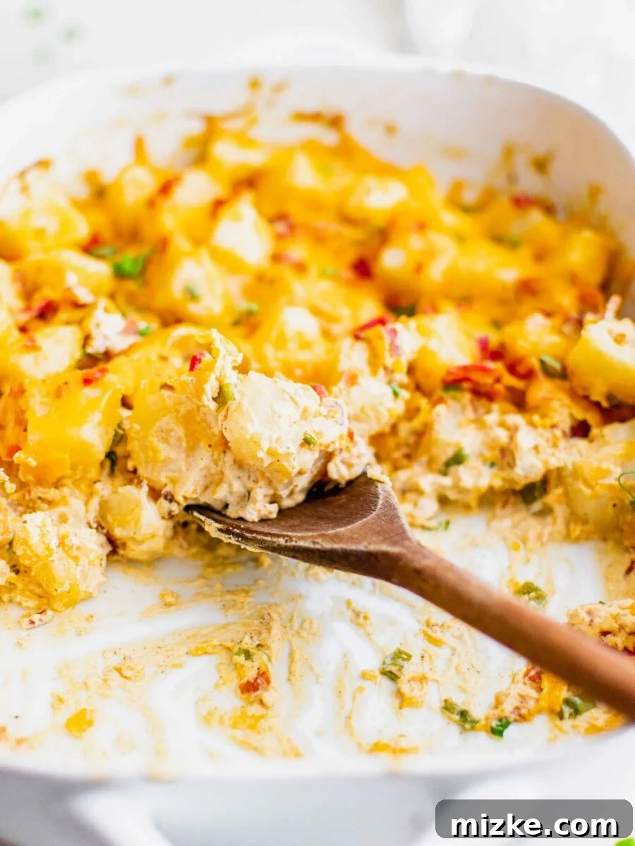 Loaded Potato Dream Bake 4 A wooden spoon is gathering a serving of potato casserole from a white dish.