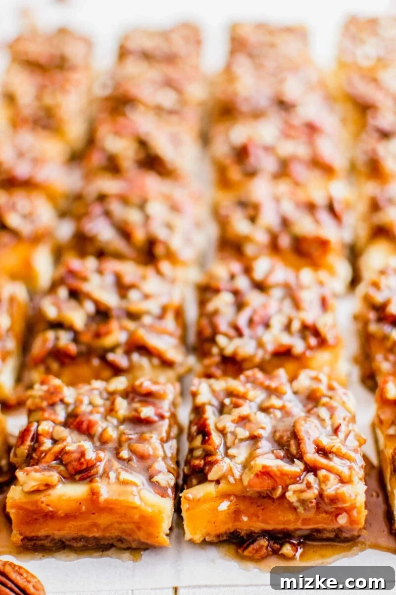 Decadent Pecan Pie Cheesecake Bars 3 Multiple cheesecake bars are topped with a generous layer of glistening, gooey pecan topping, ready to be served.