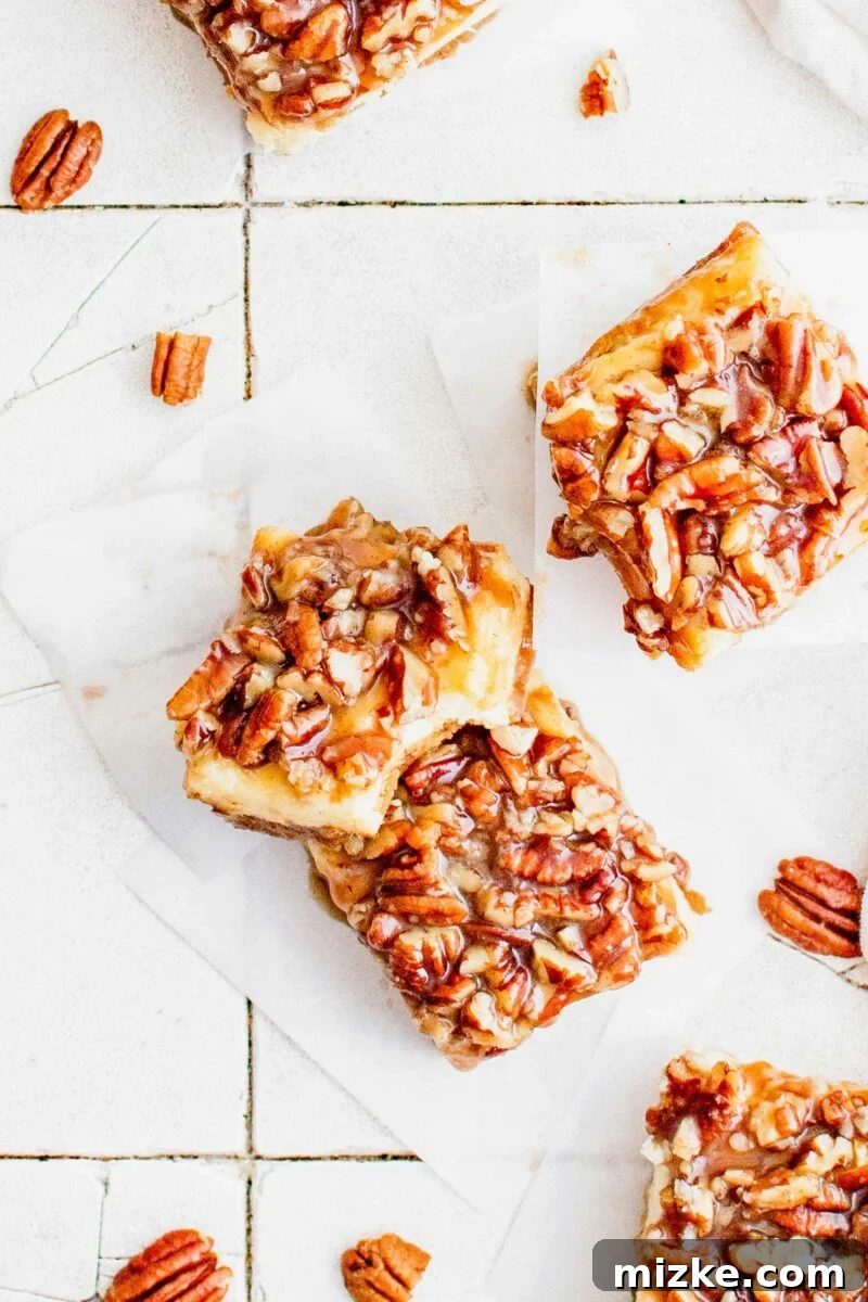 Decadent Pecan Pie Cheesecake Bars 5 A bite has been taken out of a pecan pie cheesecake bar, revealing the soft cheesecake and crunchy pecan layers.
