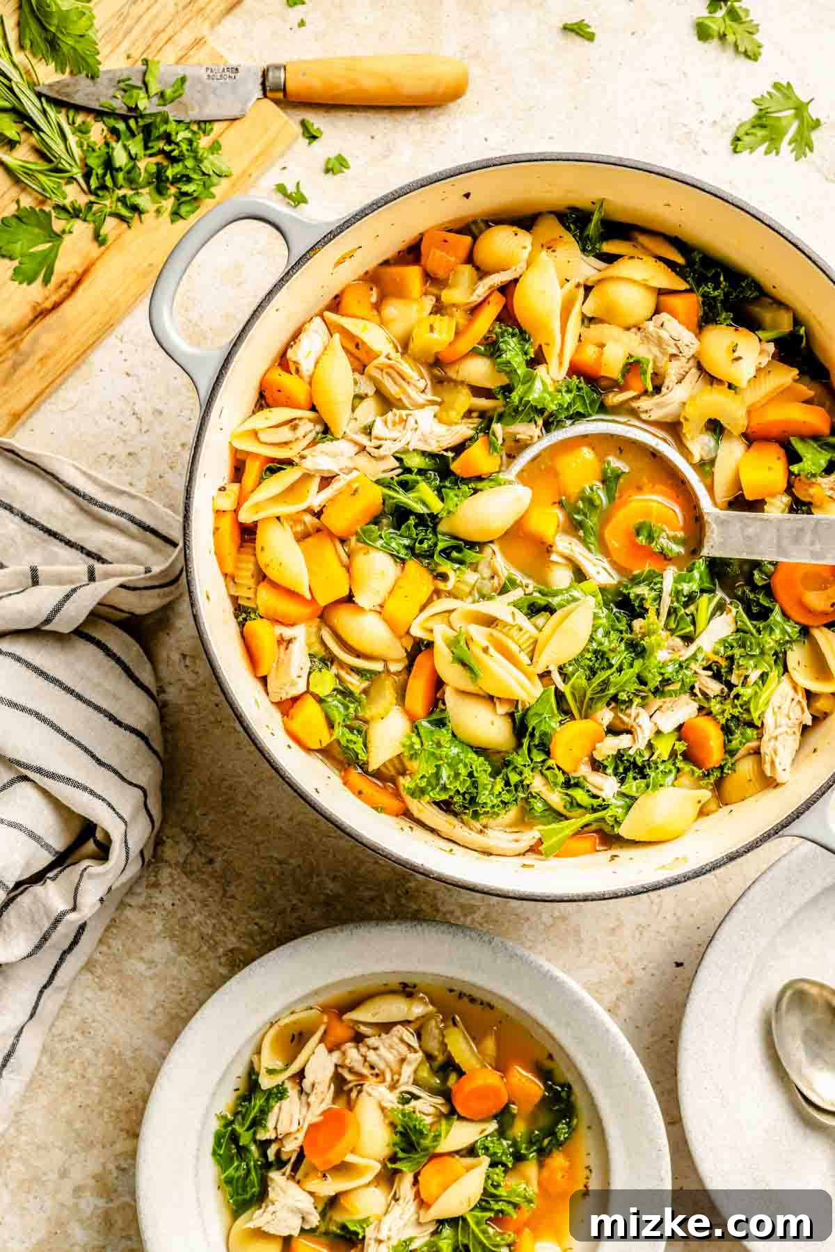 A metal spoon is in the center of the turkey vegetable soup in the Dutch oven, showcasing the rich broth and colorful vegetables.