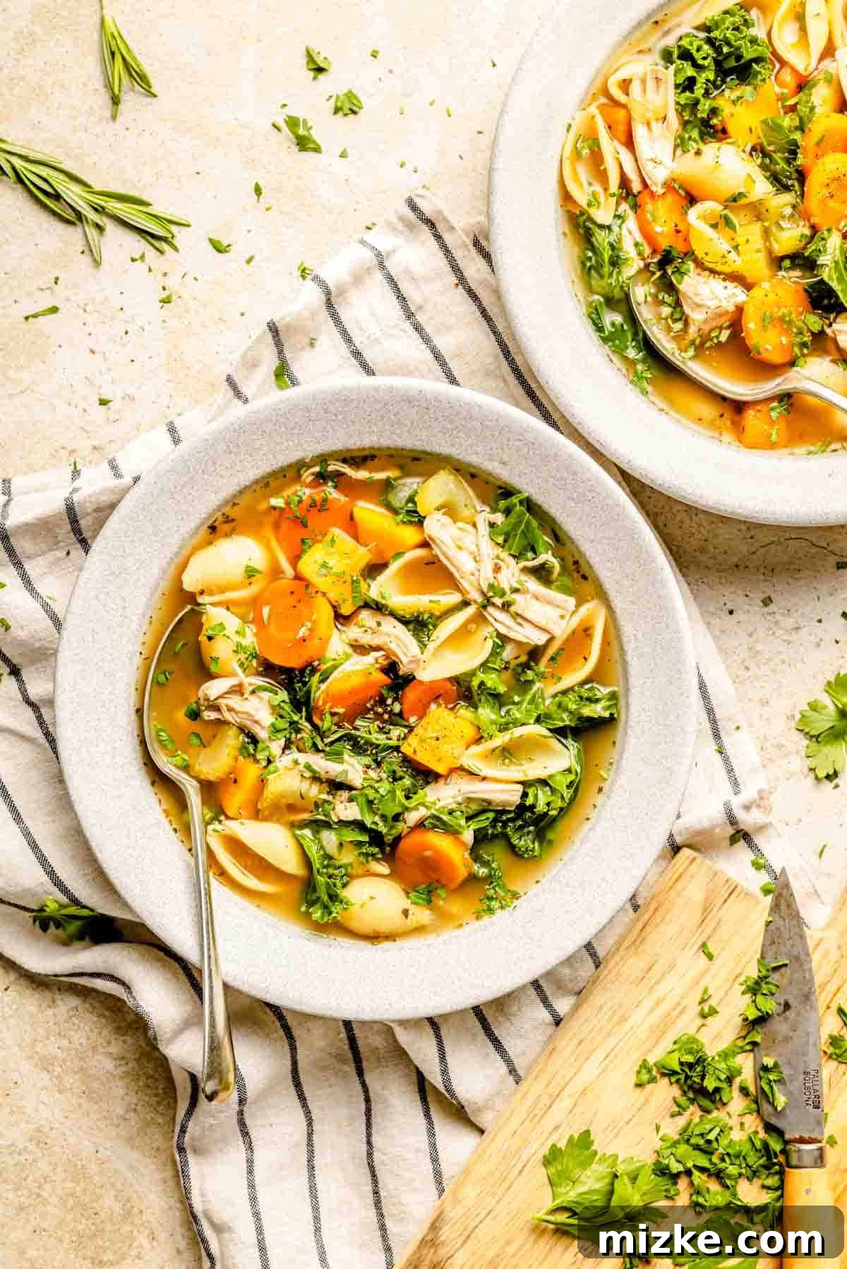 A bowl of turkey vegetable soup in a grey bowl with fresh parsley sprinkled on top, ready to eat.