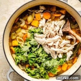 Shredded turkey and kale leaves are added to the top of the soup in the Dutch oven.