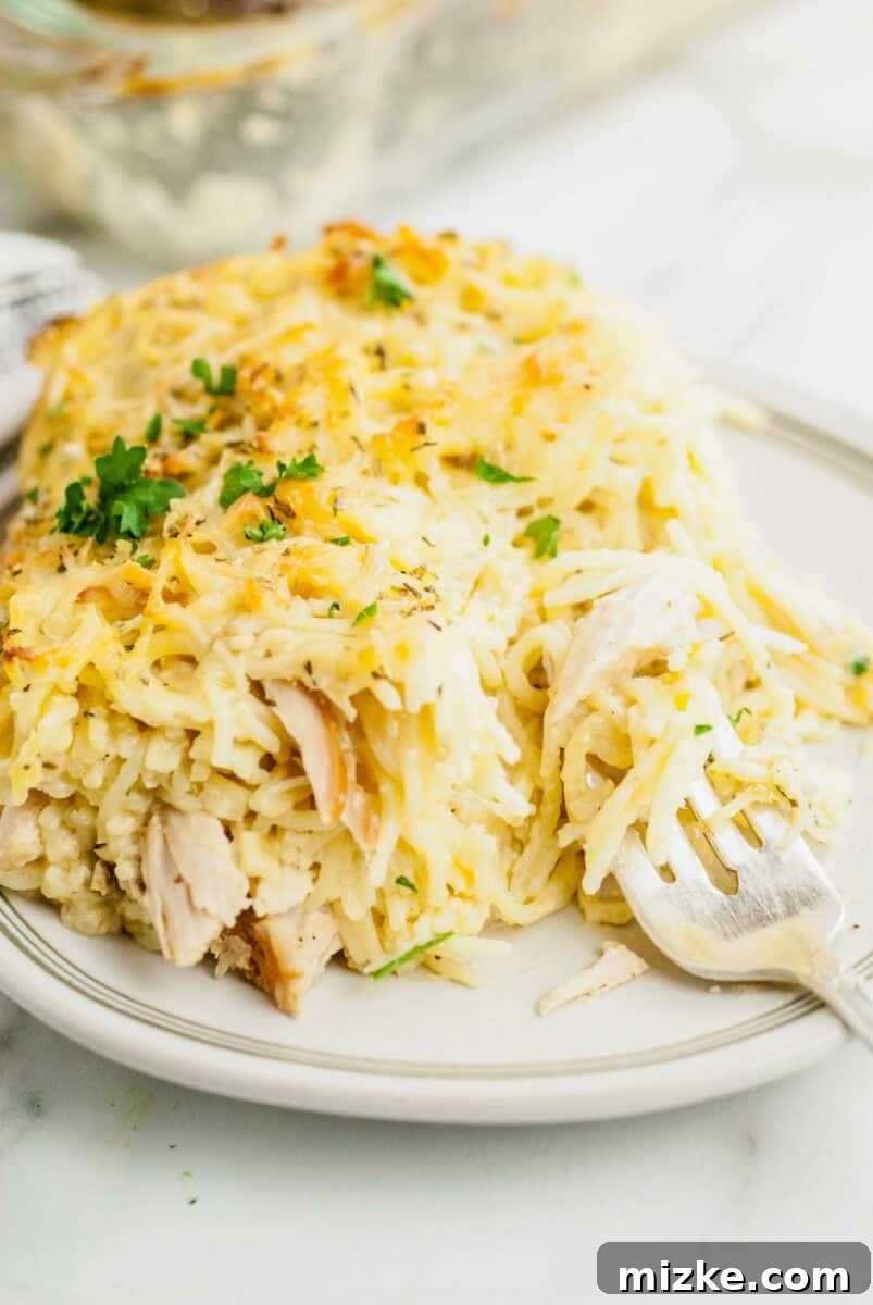 Creamy Turkey Tetrazzini 6 A fork is digging into a creamy, cheesy serving of turkey and noodles on a white plate, highlighting the dish's texture.