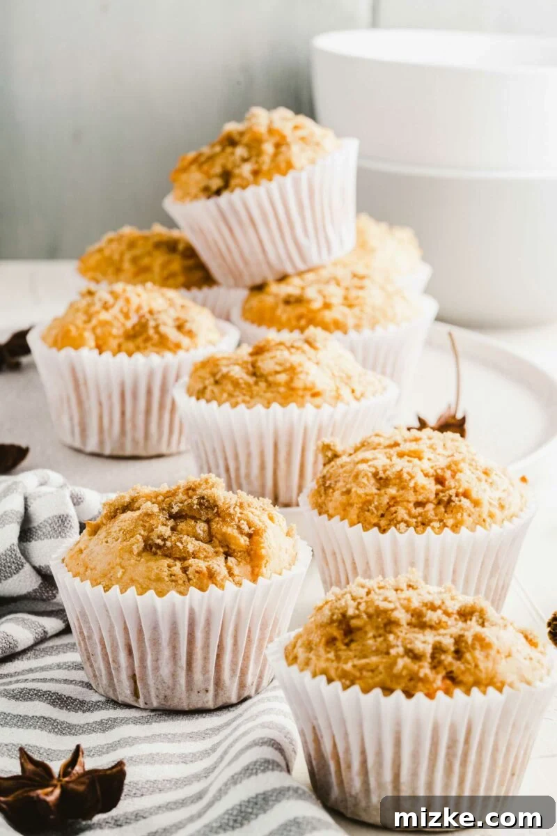 Golden Spiced Sweet Potato Muffins 3 Multiple sweet potato muffins are arranged in white cupcake wrappers, artfully placed on a stylish black and white striped tea cloth, emphasizing their inviting appeal.
