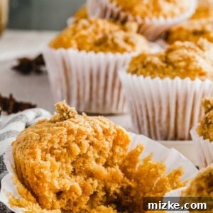 A perfectly baked sweet potato muffin is featured in a close-up shot, emphasizing its inviting texture and golden-brown top, set against a warm, rustic background.