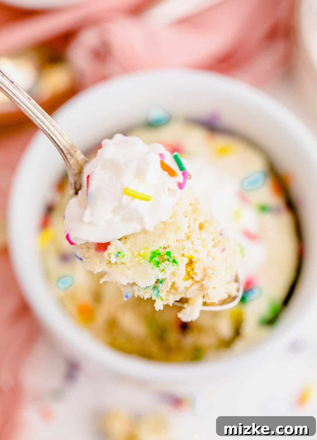 Moist Funfetti Mug Cake Bite Close-up of a spoonful of funfetti mug cake with whipped cream and colorful sprinkles