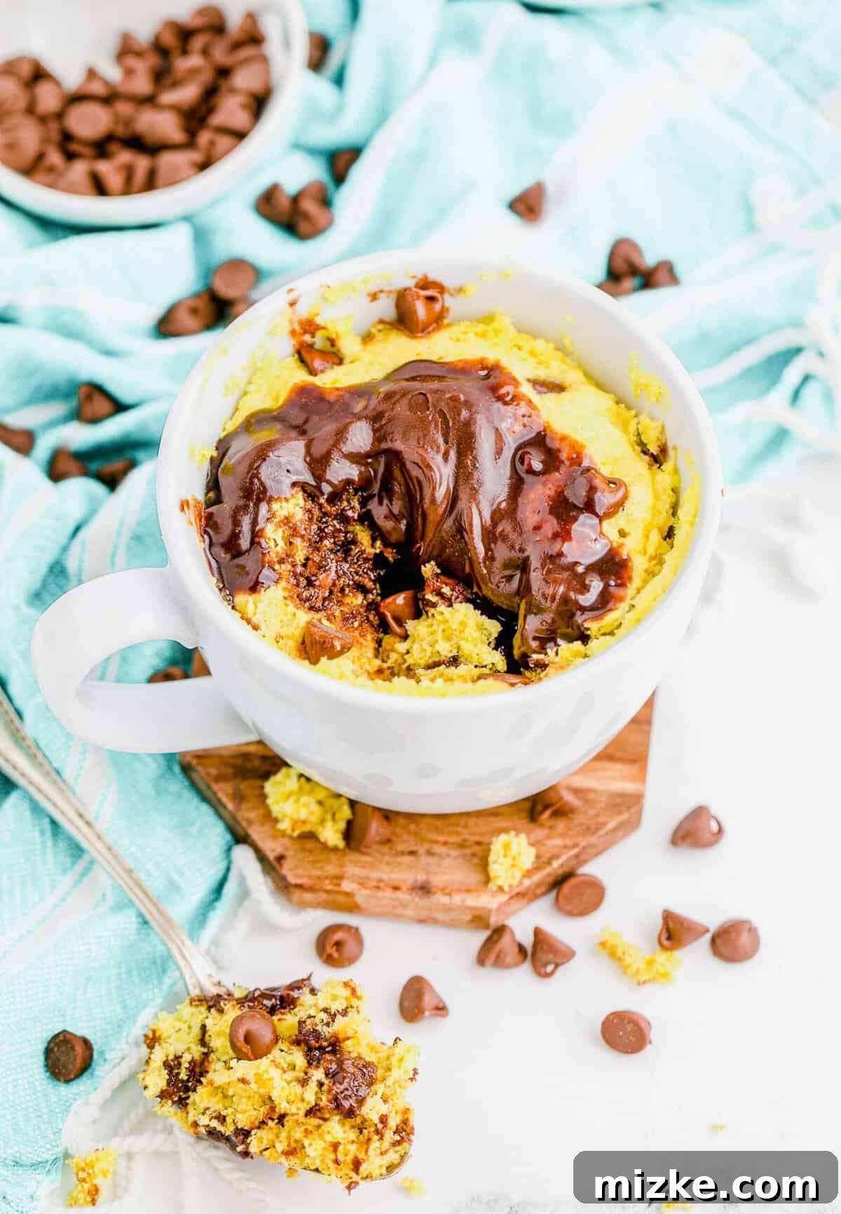 Instant Chocolate Chip Mug Treat 3 Close-up of a chocolate chip cake in a mug, with a spoon taking a scoop in the foreground