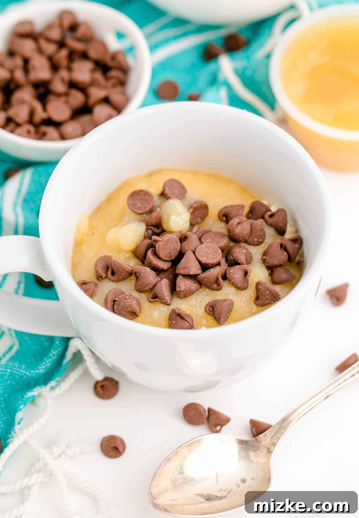 Instant Chocolate Chip Mug Treat 7 Milk chocolate chips being sprinkled on top of the applesauce and cake mix mixture in a mug