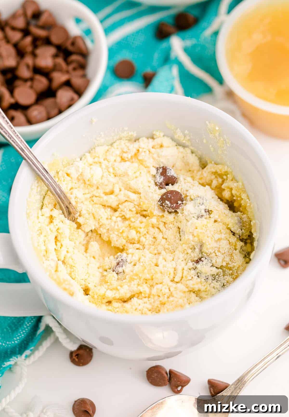 Instant Chocolate Chip Mug Treat 8 All ingredients – yellow cake mix, water, applesauce, and chocolate chips – thoroughly mixed together in a white mug to form a smooth batter
